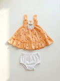 Children's orange dress with bunny design and white bloomers on a light gray background