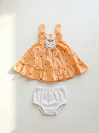 Children's orange dress with bunny design and white bloomers on a light gray background